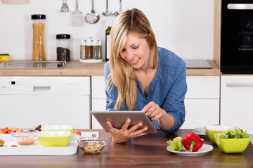 Smiling Woman Using Digital Tablet In Kitchen
