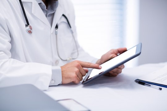Mid section of male doctor holding digital tablet