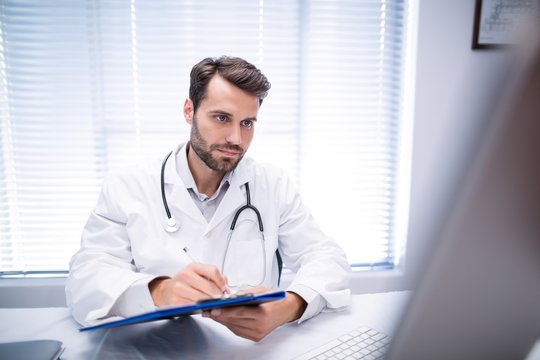 doctor writing on clipboard while working 