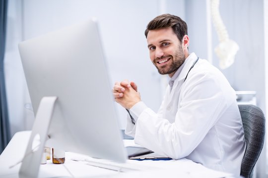 Portrait Of Male Doctor Sitting At Desk