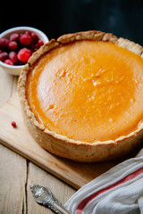 Pumpkin cheesecake with berries on wooden background. Rustic concept