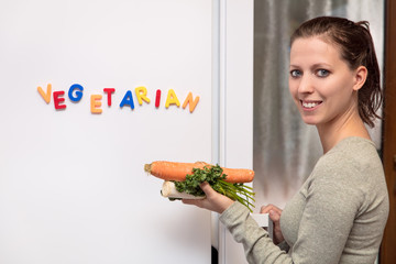 Junge Frau öffnet Kühlschrank, Gemüse in der Hand, Wort Veget