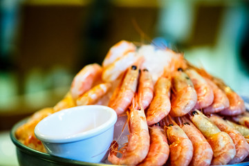 Large orange boiled shrimp laying on a plate with ice.