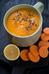 Close-up of olive-coloured cup with carrot soup, selective focus