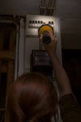 Frau beim Sicherungskasten nach einem Stromausfall, Taschenlampe