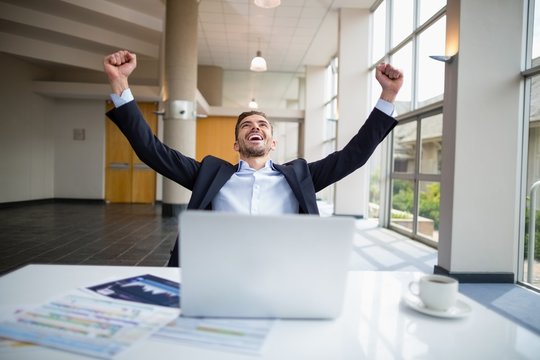 Businessman sitting at desk with arms outstretched