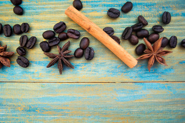 coffee beans, cinnamon sticks and star anise on wooden background painted in blue and gold. place for text.