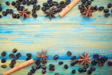 coffee beans, cinnamon sticks and star anise on wooden background painted in blue and gold. place for text.