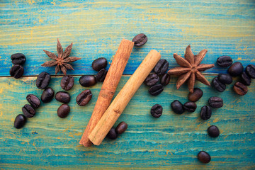 coffee beans, cinnamon sticks and star anise on wooden background painted in blue and gold. place for text.