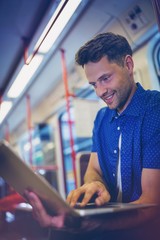 Handsome man using laptop in train