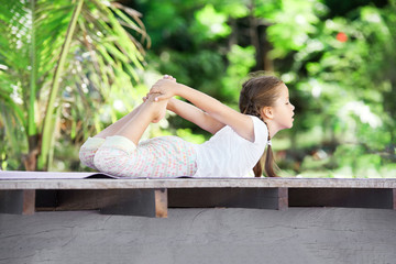 Obraz na płótnie Canvas Child doing exercise on platform outdoors. Healthy lifestyle. Yoga girl