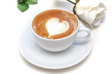 Coffee cup of heart shape latte art on the plate with white rose