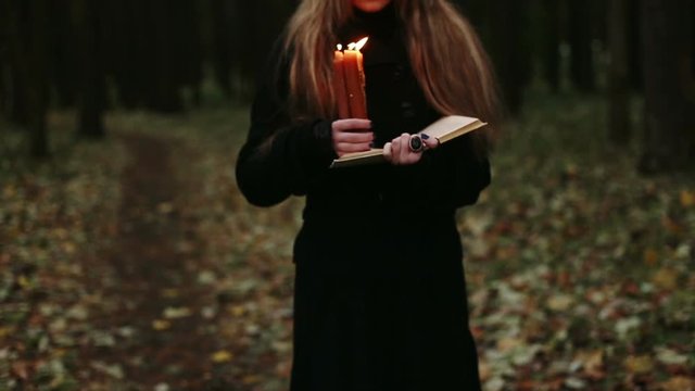 Witch with a book and candles in the forest