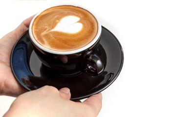 Coffee cup with heart shape latte art on top, hands serving the
