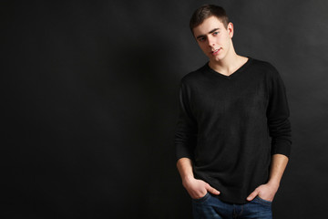 Young handsome guy posing in the studio on a black background.