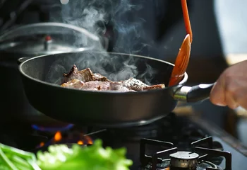 Photo sur Aluminium Cuisinier Cuisson de la viande dans une poêle