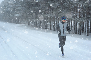 Female running sprinting up a snowy road during a winter trainin