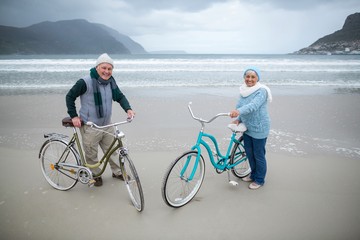 Fototapeta premium Senior couple standing with bicycles on the beach 