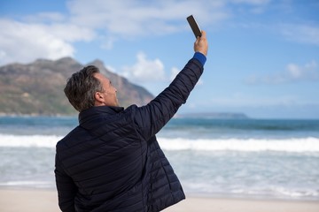 Mature man taking a selfie from mobile phone on the beach