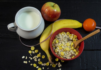 Breakfast with muesli, fruits and milk on black background
