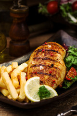grilled chicken breast with green salad and french fries.