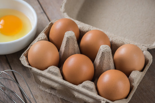 Eggs in carton box and yolk in bowl