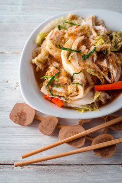 Bowl with kimchi on the white wooden table vertical