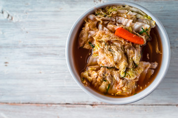 Ceramic bowl  with Korean kimchi on the white wooden table top view