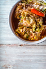 Ceramic bowl  with Korean kimchi on the white wooden table