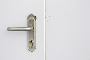 Metal handle and keyhole on worn white door