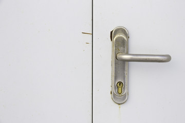 Battered doorknob and keyhole on white door