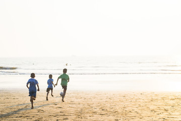 Fototapeta na wymiar Kids playing football on sandy beach of Indian sea