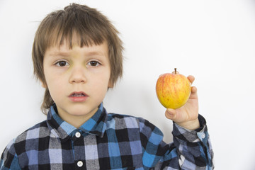 Boy in blue shirt is holding apple and looking ahead