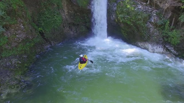 AERIAL: Kayaker paddling towards plunge pool of raging whitewater waterfall