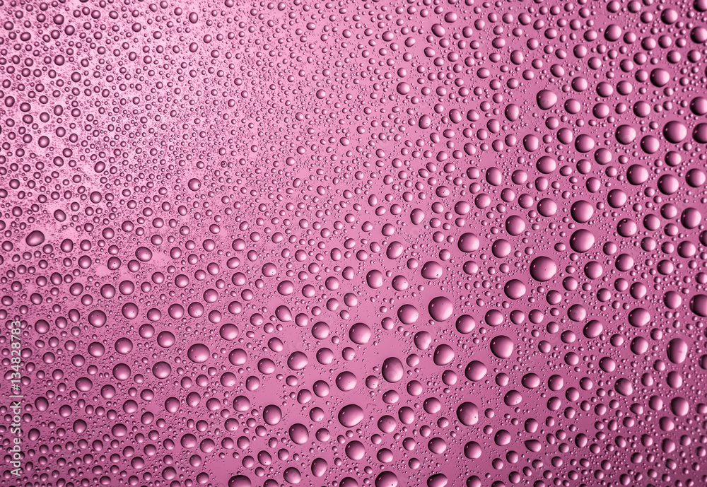 Wall mural misted glass with drops water close up on pink background