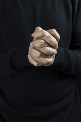 The wrinkled hands of an old man praying God. Detail close-up shot. Neat colors.
