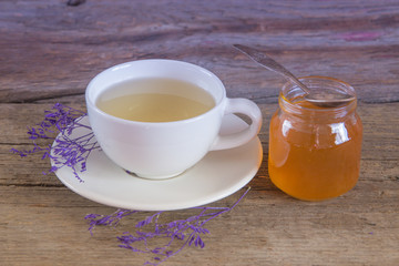 Cup of tea with honey in jar on the wooden table