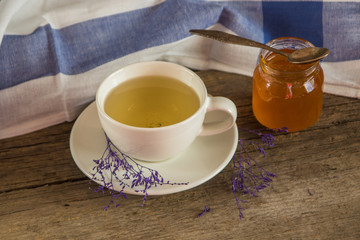 Green tea in a white cup and jar of honey with spoon and blue ki