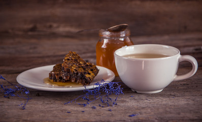 Honeycombs and honey in jar and green tea on wooden background