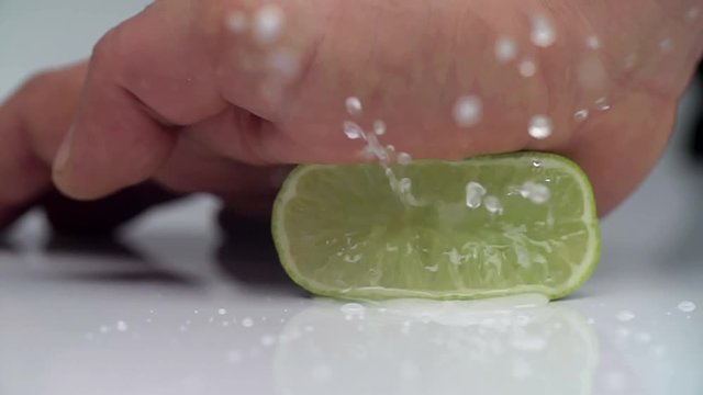 SLOW MOTION LIME: Hand squeezes the juice from the lime close up