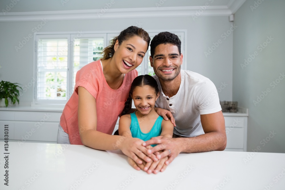 Wall mural Portrait of parents and daughter standing together in kitchen