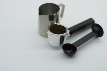 Espresso machine group with blurred milk jug and coffee scoop.