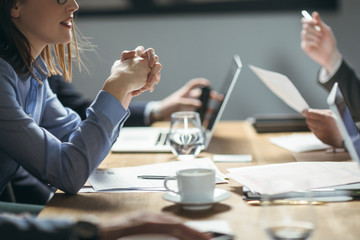 Unrecognisable cropped businesspeople working and sitting at mee