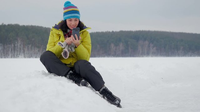 Young woman taking some happy selfies at outdoor forest skating rink.
