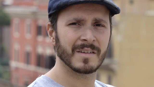 angry man with hat, rants looking at the camera