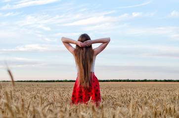 Girl standing in a wheat field with his hands behind his head, the night sky seen from behind