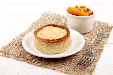 scottish pie on a plate and a bowl with pea and carrot
