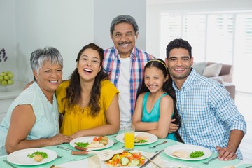 Happy multi generation family having meal on table at home
