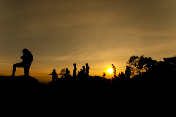 silhouette of people relax at the cliff and mountains with sunset in the evening