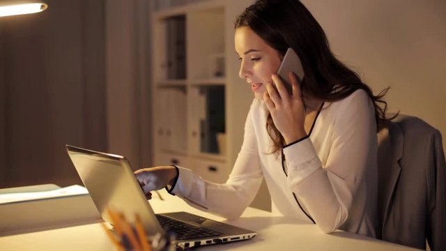 woman with laptop calling on smartphone at office